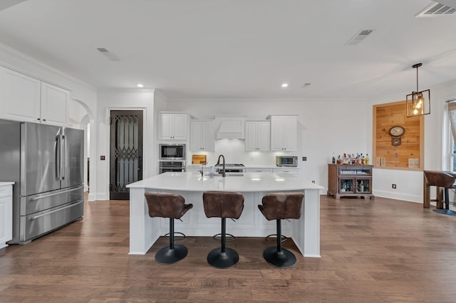 kitchen with appliances with stainless steel finishes, pendant lighting, a spacious island, and white cabinetry