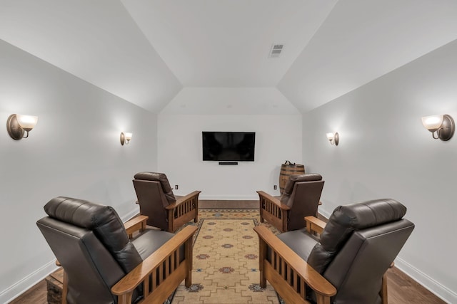 cinema room featuring hardwood / wood-style flooring and lofted ceiling