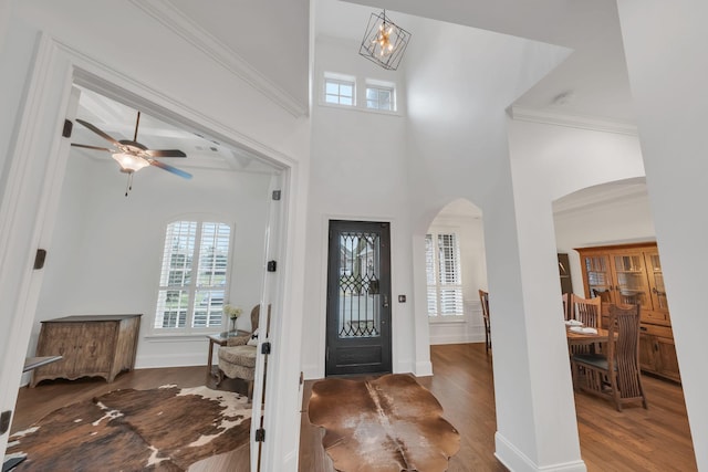 entrance foyer featuring ceiling fan with notable chandelier, dark wood-type flooring, and ornamental molding