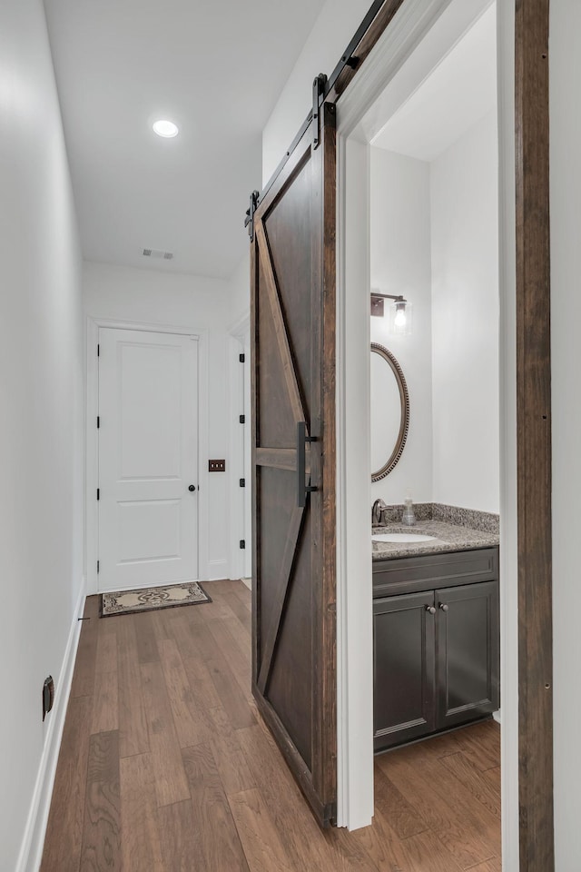 hallway with a barn door, wood-type flooring, and sink