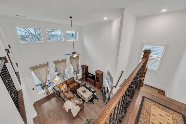 living room featuring ceiling fan, a towering ceiling, and hardwood / wood-style floors