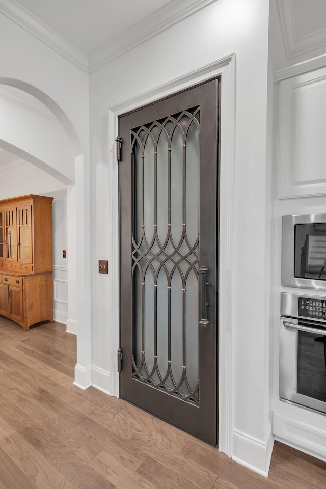 entrance foyer with ornamental molding and light hardwood / wood-style flooring