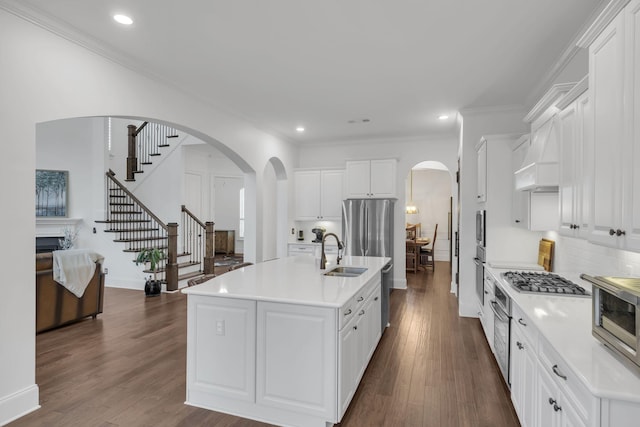 kitchen featuring sink, a kitchen island with sink, stainless steel appliances, custom range hood, and white cabinets