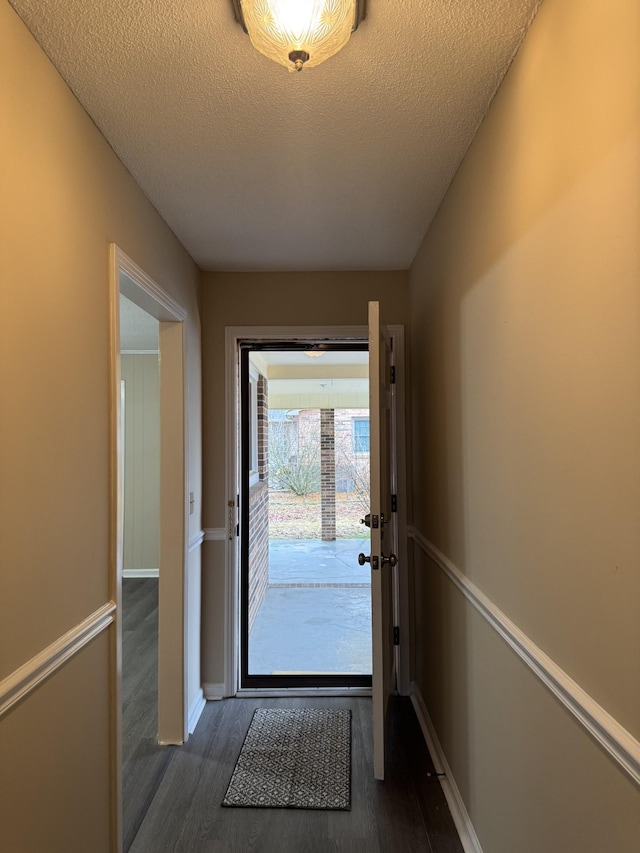 doorway featuring dark wood-type flooring and a textured ceiling