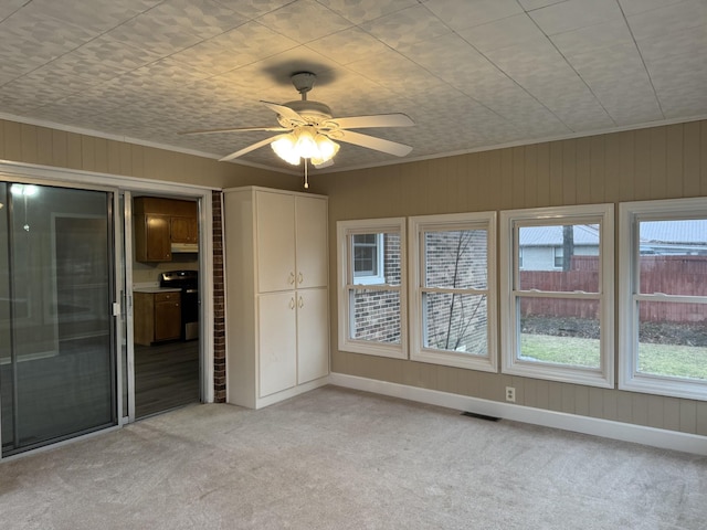 interior space with light carpet, ornamental molding, and ceiling fan