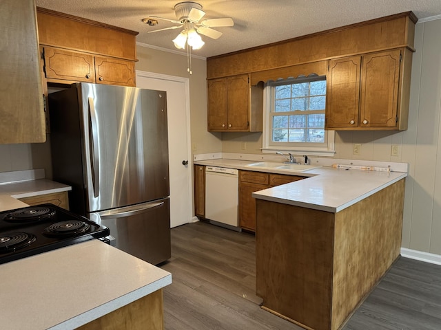 kitchen featuring sink, dark wood-type flooring, appliances with stainless steel finishes, ornamental molding, and a textured ceiling