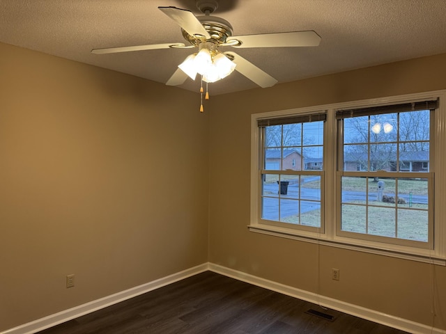 empty room featuring ceiling fan, dark hardwood / wood-style floors, and a textured ceiling