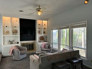 carpeted living room featuring built in shelves and ceiling fan