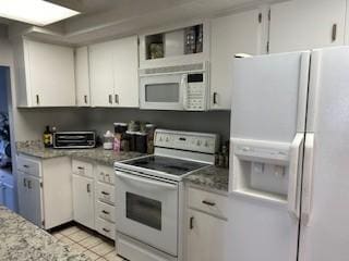 kitchen with white cabinetry, white appliances, light stone countertops, and light tile patterned flooring