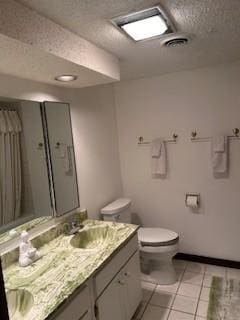 bathroom featuring a shower with shower curtain, vanity, a textured ceiling, tile patterned floors, and toilet