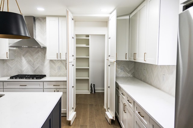 kitchen featuring white cabinetry, wall chimney exhaust hood, decorative light fixtures, and stainless steel gas cooktop