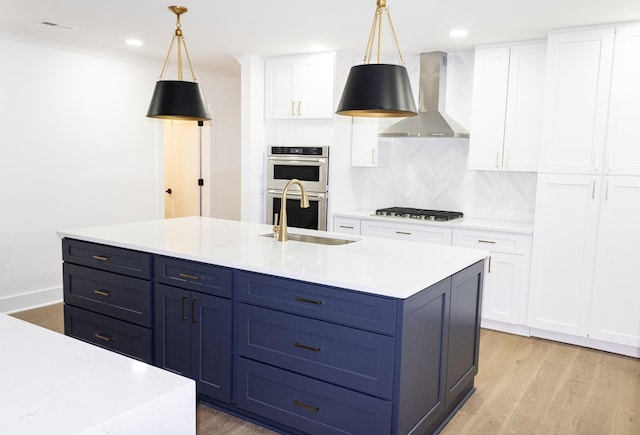 kitchen featuring stainless steel appliances, white cabinetry, hanging light fixtures, and wall chimney exhaust hood