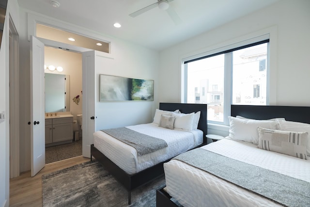 bedroom with dark wood-type flooring, ceiling fan, and connected bathroom