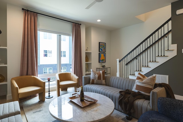 living room with ceiling fan, built in shelves, and light hardwood / wood-style flooring