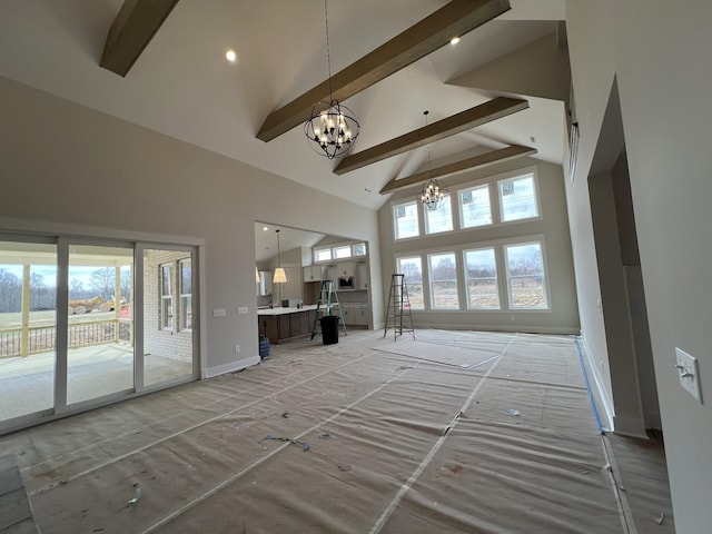 unfurnished living room with a chandelier, high vaulted ceiling, beamed ceiling, and a wealth of natural light