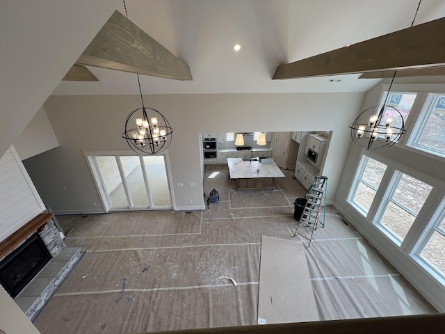 unfurnished living room with baseboards, a high ceiling, a chandelier, and a fireplace with raised hearth