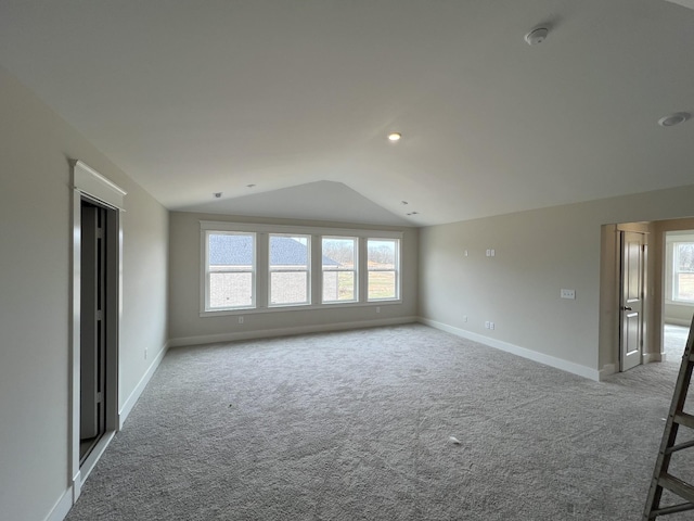 carpeted spare room with baseboards and vaulted ceiling