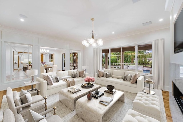 living room with light wood-type flooring, an inviting chandelier, and crown molding