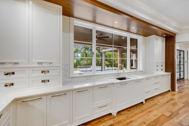 kitchen with ceiling fan, light wood-type flooring, sink, and white cabinetry