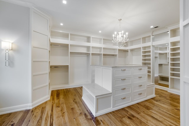 spacious closet featuring light hardwood / wood-style flooring and a notable chandelier