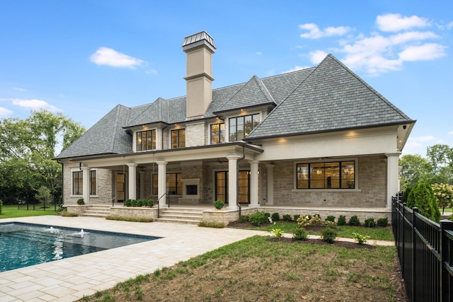 back of property featuring a fenced in pool, a patio area, and a lawn