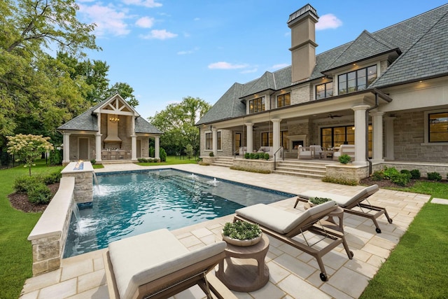 view of swimming pool with pool water feature, an outdoor fireplace, a patio, and ceiling fan