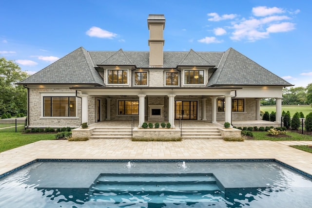 rear view of house with pool water feature, a patio area, and a fenced in pool