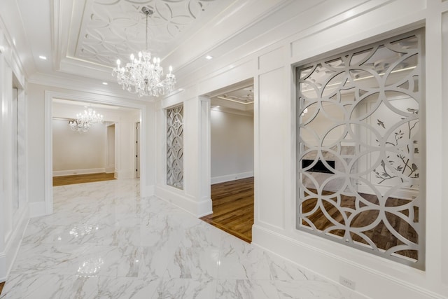 hallway featuring crown molding, a raised ceiling, and a notable chandelier