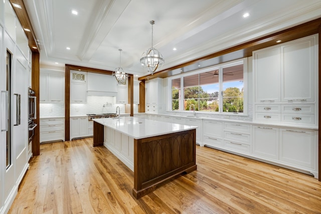 kitchen featuring hanging light fixtures, white cabinetry, light hardwood / wood-style floors, and a center island