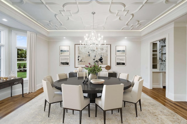 dining space with crown molding, wood-type flooring, and an inviting chandelier