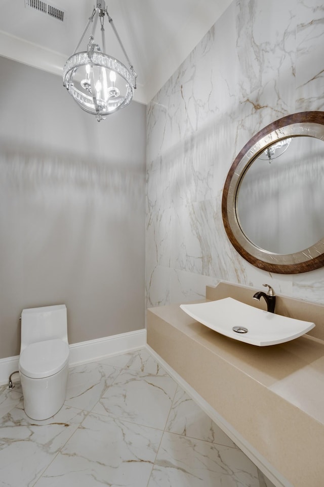 bathroom with sink, toilet, and an inviting chandelier