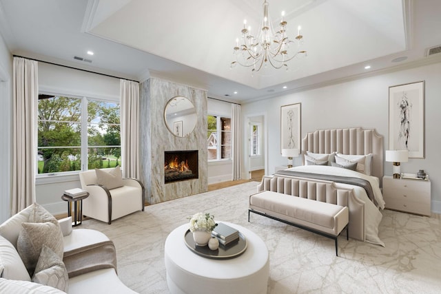 bedroom with a raised ceiling, a high end fireplace, multiple windows, and a notable chandelier