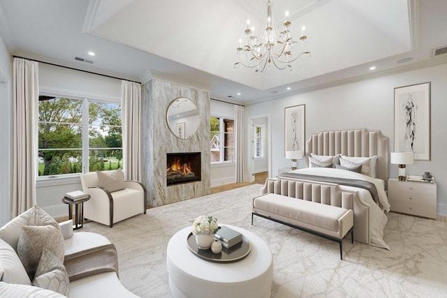 bedroom with a chandelier, a tray ceiling, and a premium fireplace