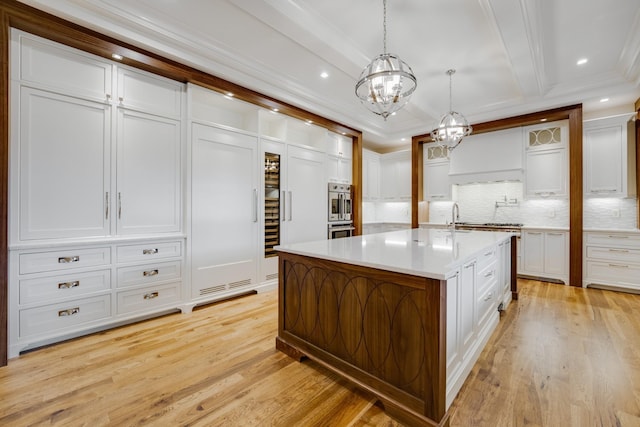 kitchen featuring light hardwood / wood-style floors, tasteful backsplash, pendant lighting, white cabinets, and a center island