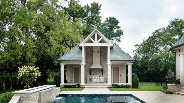 view of swimming pool featuring a grill, a patio, an outdoor stone fireplace, an outdoor kitchen, and an outdoor structure