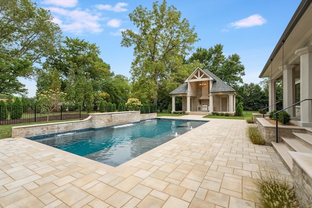 view of swimming pool featuring pool water feature, an outbuilding, an outdoor fireplace, and a patio