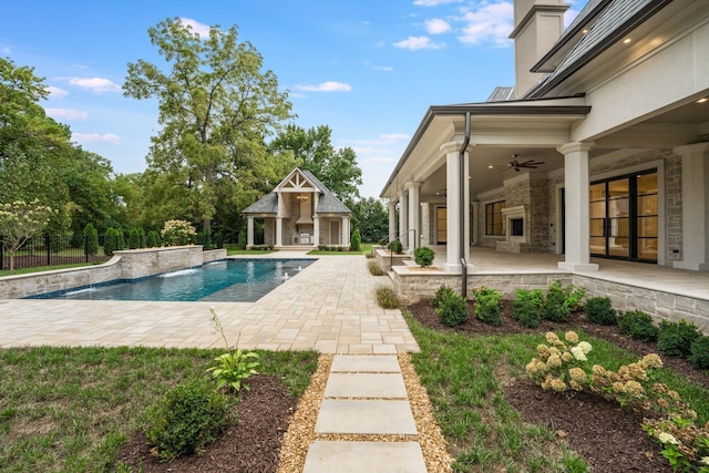 view of swimming pool featuring ceiling fan, a patio area, an outbuilding, and a fireplace