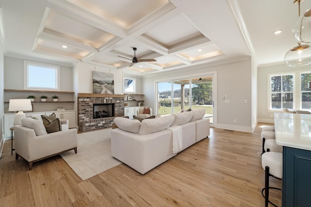 living room featuring a brick fireplace, light wood-type flooring, ceiling fan, and coffered ceiling