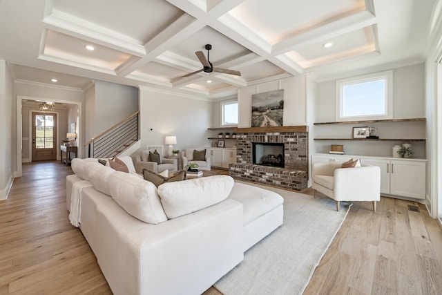 living room featuring beamed ceiling, a fireplace, light hardwood / wood-style floors, ceiling fan, and coffered ceiling