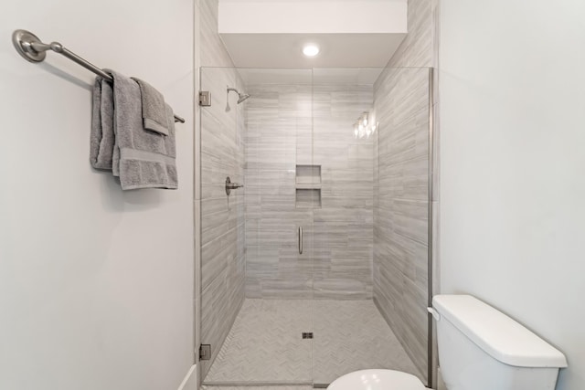 bathroom featuring toilet and a shower with door