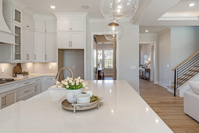 kitchen featuring hanging light fixtures, white cabinets, and custom exhaust hood