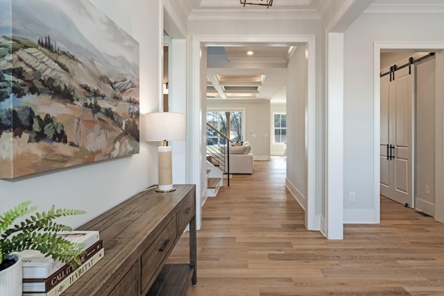 hallway with beam ceiling, light wood-type flooring, crown molding, a barn door, and coffered ceiling