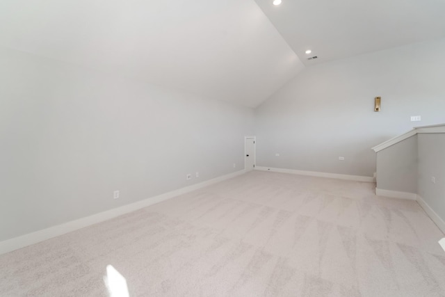 additional living space featuring vaulted ceiling and light colored carpet