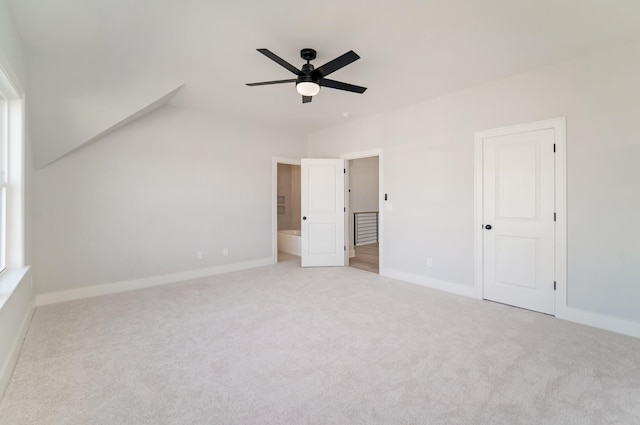 unfurnished bedroom featuring ceiling fan, light colored carpet, and ensuite bath