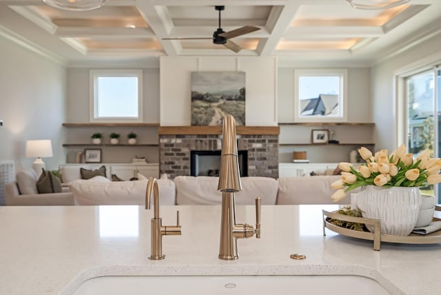 kitchen featuring coffered ceiling, ceiling fan, beamed ceiling, ornamental molding, and sink