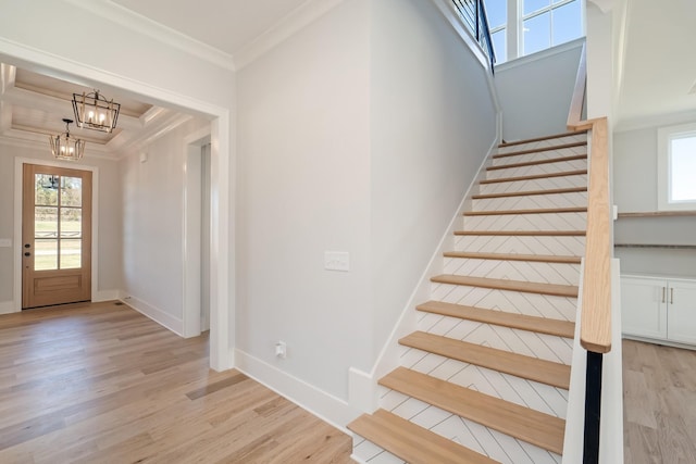 stairway with an inviting chandelier, ornamental molding, and wood-type flooring