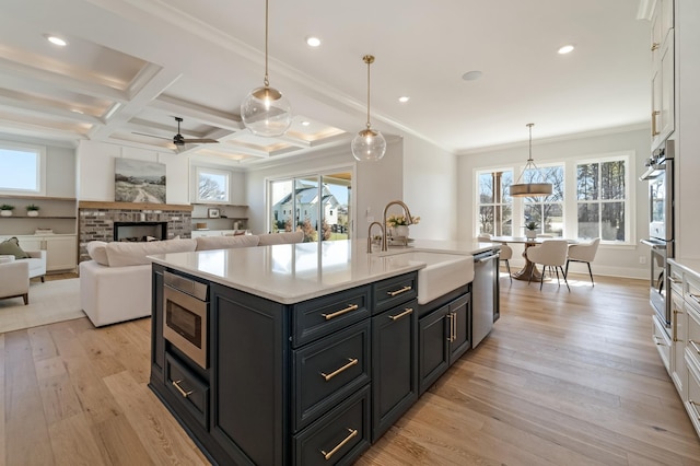 kitchen with decorative light fixtures, a brick fireplace, sink, white cabinetry, and appliances with stainless steel finishes