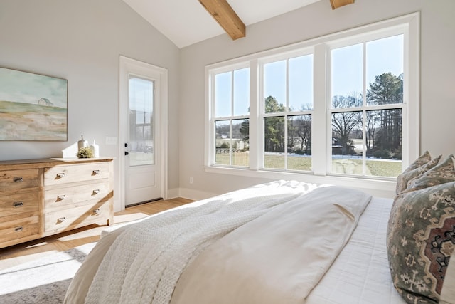 bedroom with lofted ceiling with beams and light hardwood / wood-style flooring