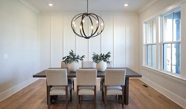 dining room featuring a wealth of natural light, hardwood / wood-style floors, crown molding, and an inviting chandelier