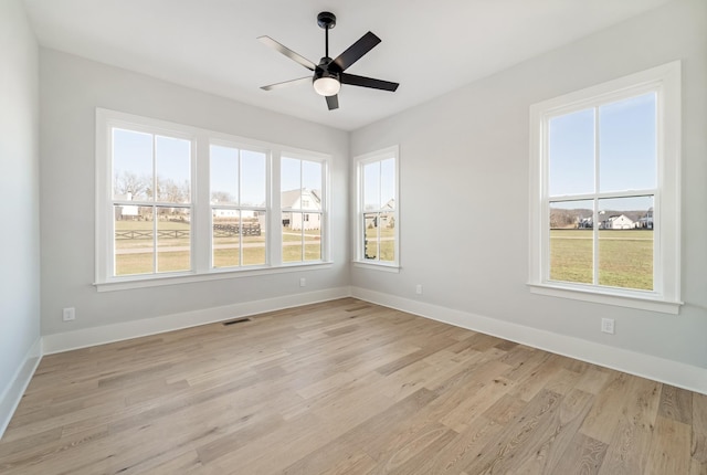 empty room with light wood-type flooring, ceiling fan, and plenty of natural light